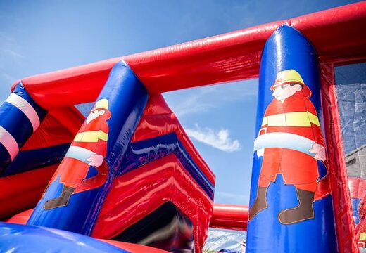Opblaasbaar overdekt springkasteel in thema brandweer met een glijbaan op het springvlak, klimtoren en leuke obstakels voor kids. Koop springkastelen online bij JB Inflatables Nederland