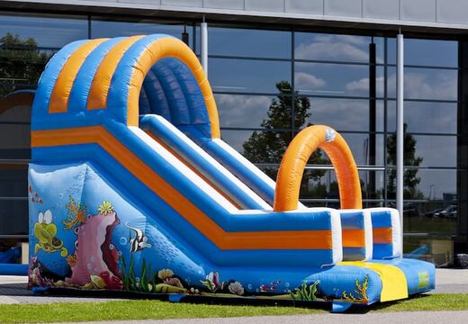Oceanworld slide glijbaan met de vrolijke kleuren en leuke print op de achterwand kopen. Bestel opblaasbare glijbanen nu online bij JB Inflatables Nederland